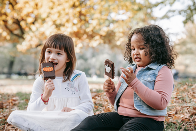 Two kids eating Halloween treats on a stick