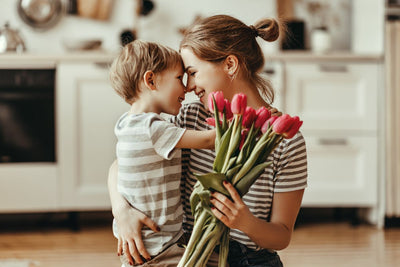 A mother and child while she holds a bouquet of tulips.