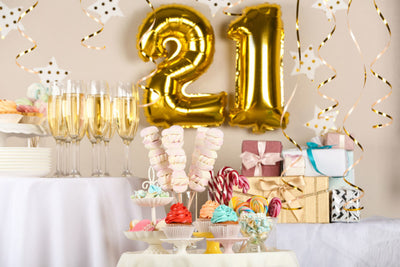 Birthday dessert table with champagne and '21' balloons.