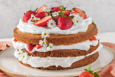 Naked cake with strawberries, buttercream, flowers.