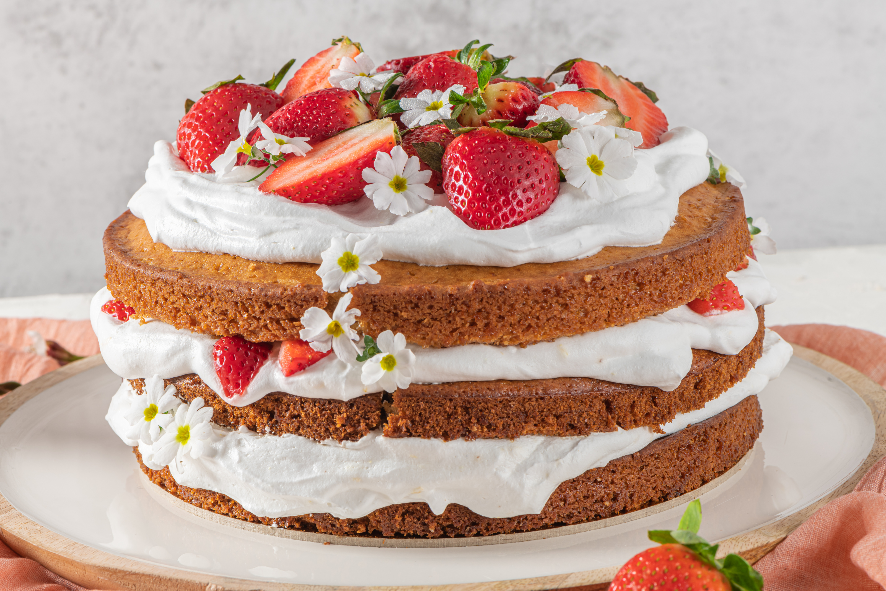 Naked cake with strawberries, buttercream, flowers.