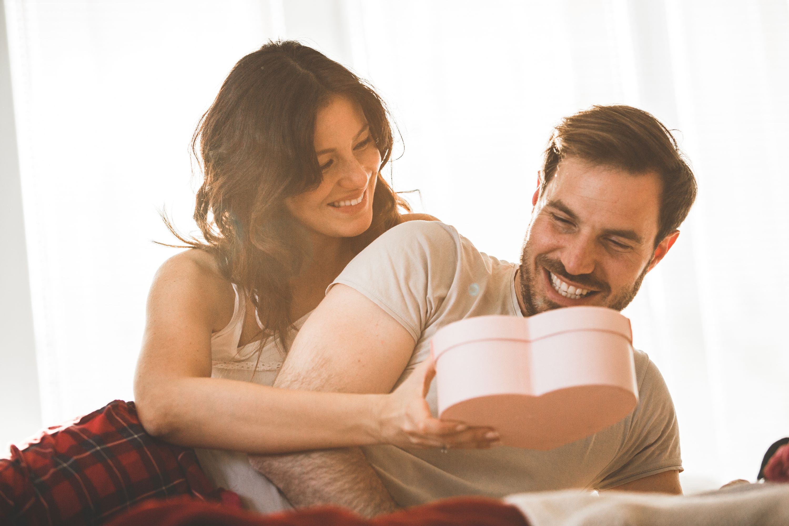 Woman giving gift bo in shape of heart to her boyfriend.